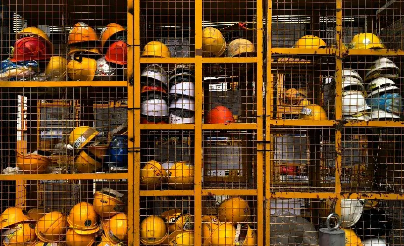 A large group of yellow construction helmets in a cage.