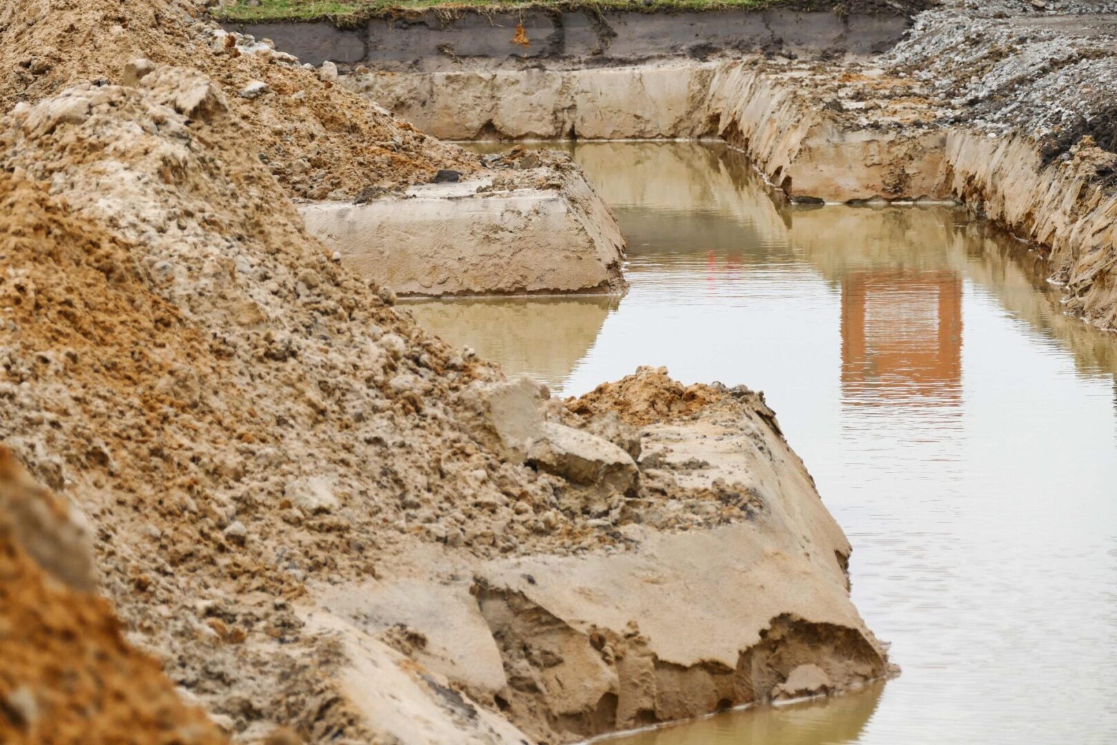 A dirt field with water and rocks in it