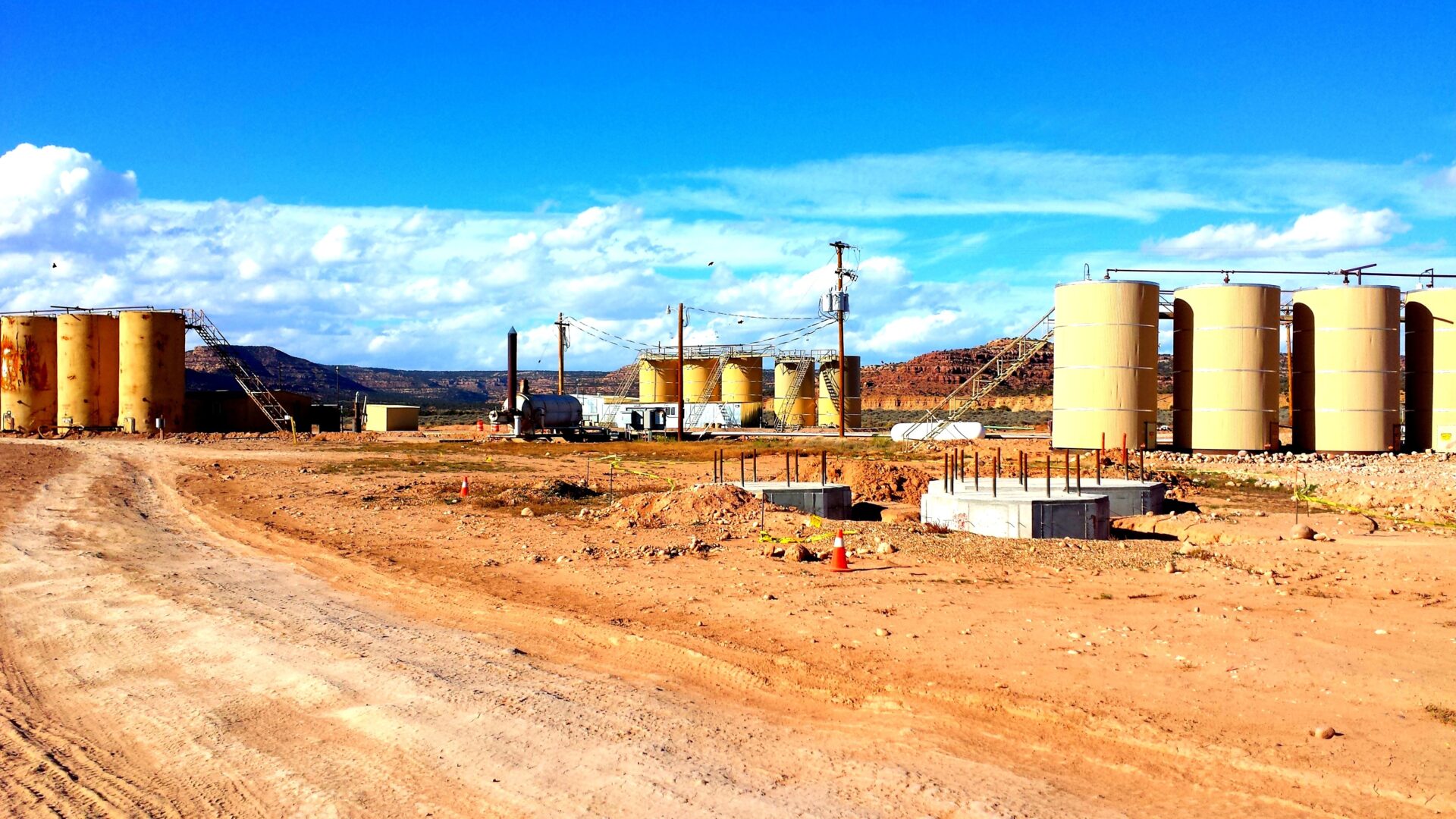 A dirt road with several tanks in the background.