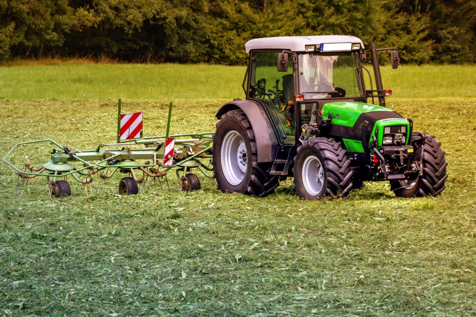 A green tractor is pulling a plow across the field.