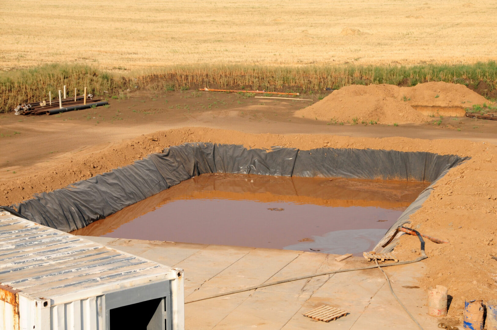 A pool of water in the middle of an empty field.