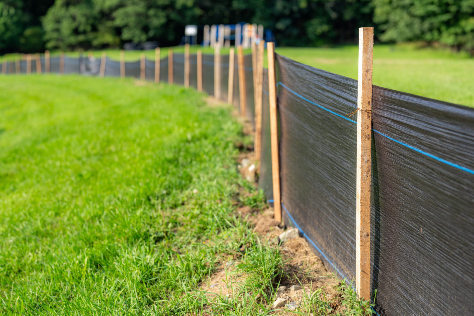 A fence that is made of wood and has black plastic covering it.